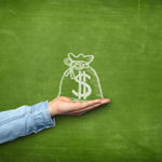 Money bag icon on blackboard with hand