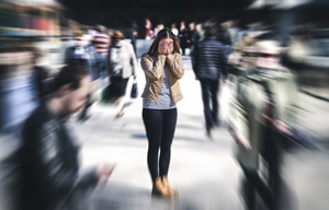 Woman overwhelmed with anxiety surrounded by people walking in busy street. Coping with anxiety, perfectionism, and ADHD.