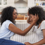 Mother Talking With Unhappy Teenage Daughter On Sofa