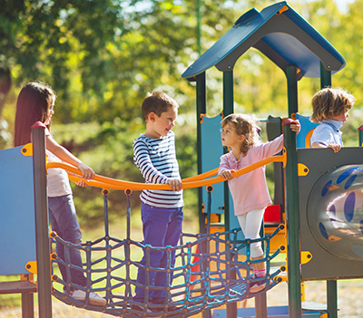 Small group of children having good time at jungle gym and talking.